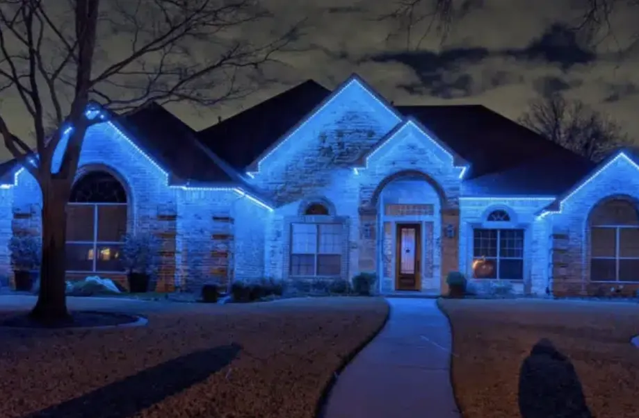 Stone-front house washed in cool blue light along the roof and door.