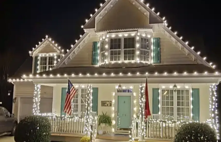 White cottage with teal shutters and a single clean string of lights along the eave.