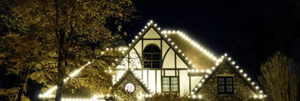 Tudor-style house at night with every gable trimmed in white lights.